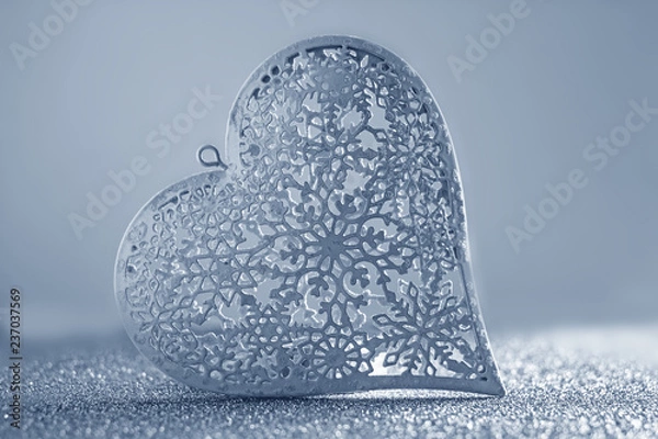 Fototapeta Valentines day background. White metal lacy heart on a silver background. Background about love, background with heart, background to the day of lovers