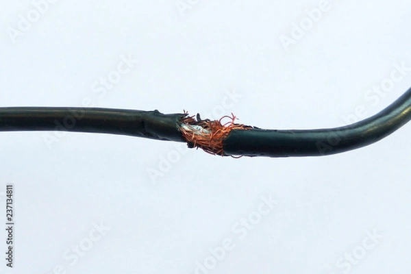 Fototapeta Damaged black electric cord on white background. Dangerous broken power electrical cable