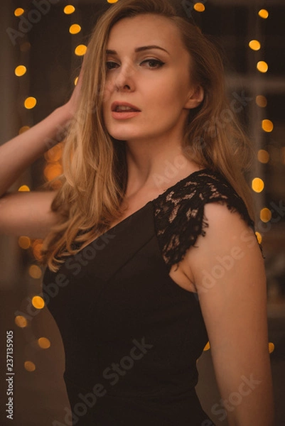 Obraz Portrait of Beautiful Woman in Lights. Fashion Dress and MakeUp. Christmas Santa. Elegant Lady in Red Dress over Christmas Tree Lights Background. Happy New Year.