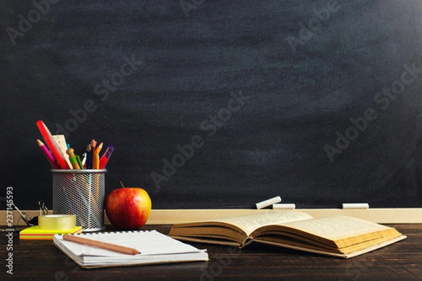 Fototapeta Teacher's desk with writing materials, a book and an apple, a blank for text or a background for a school theme. Copy space.