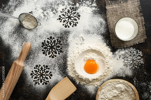Fototapeta Christmas or New Year background with baking ingredients, snowflake, flour, egg, milk, rolling pin, paddle. Top view, place for text.