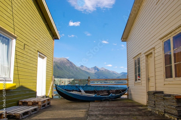 Obraz Old little blue boat and a fishing net in picturesque and colorful Norwegian town scenery; fjord background
