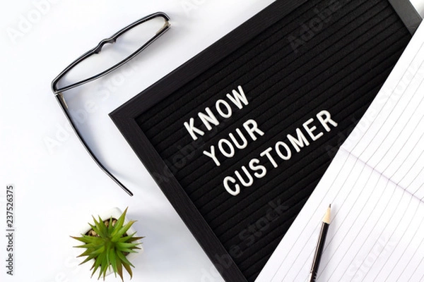 Fototapeta Know Your Customer - business concept, white text message on black board with green plant