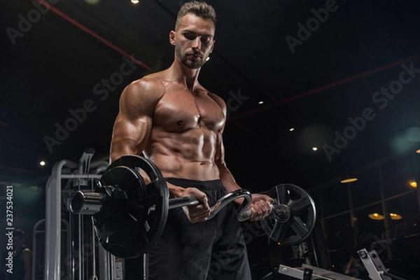 Fototapeta Handsome man with big muscles, posing at the camera in the gym