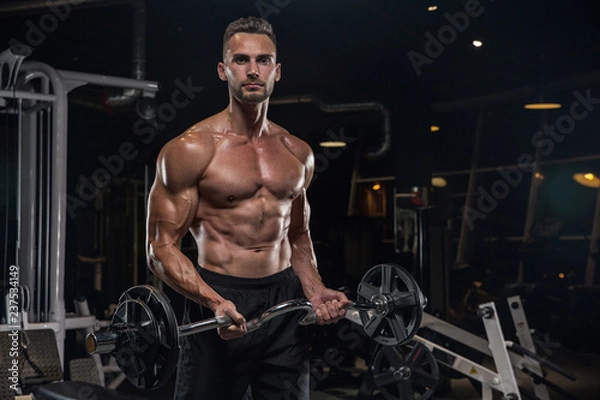 Fototapeta Handsome man with big muscles, posing at the camera in the gym