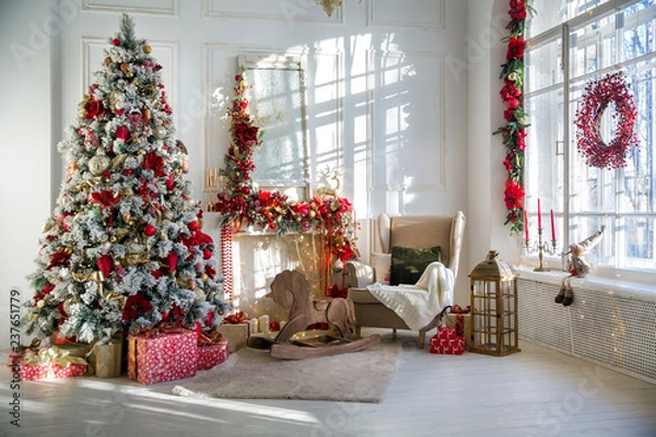 Obraz White room interior in red tones with New Year tree decorated, present boxes and artificial fireplace