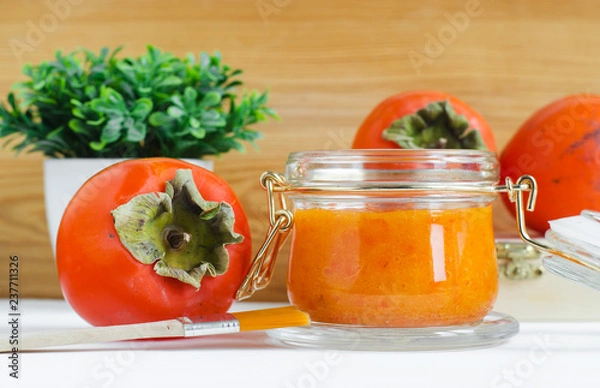 Fototapeta Homemade persimmon (kaki) face mask in a glass jar. DIY cosmetics and spa. Copy space.  