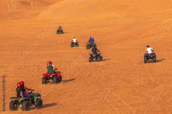 Fototapeta Tourists having fun riding Quad Bikes in dunes of Dubai Adventure Tour