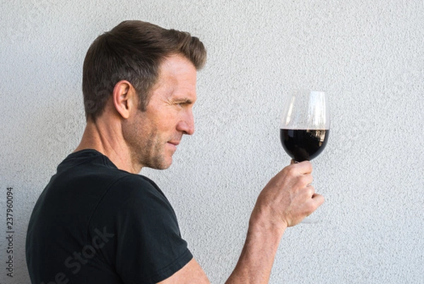Obraz profile of a handsome Caucasian man holding a glass of red wine