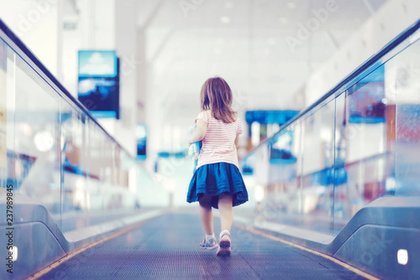 Obraz Little girl with blue toy running down the escalator in international airport terminal.