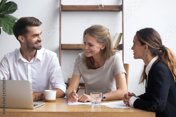 Obraz Diverse businesswomen businessman sitting at office desk use laptop reviewing documents. Cheerful workmates take brake joking or discuss project share thoughts business ideas feel good and satisfied