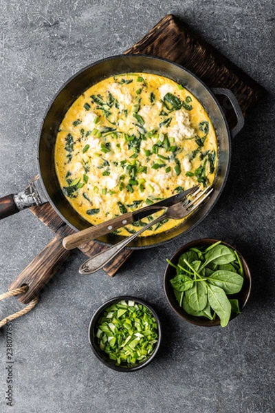 Obraz omelette with spinach and cheese in a pan on the concrete background top view