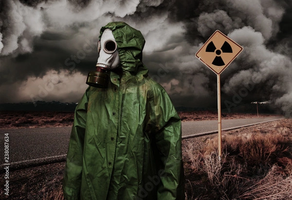 Fototapeta Man in gas mask with radiation area caution sing. Nature protection concept