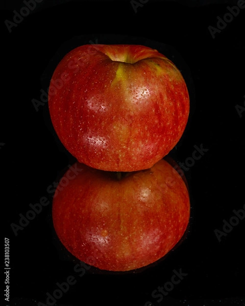 Fototapeta Red apple on mirror with black background.