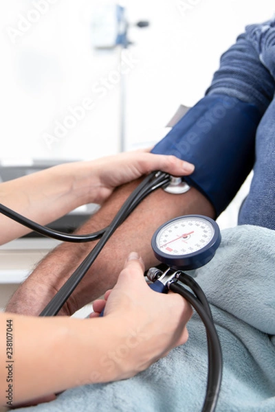 Obraz young pretty blonde nurse nurses an elderly patient in the hospital and measures his blood pressure with a cuff and prepares to inject with a syringe