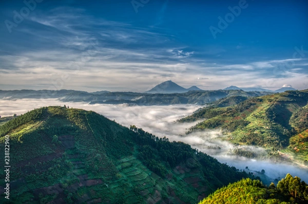 Obraz Morning in Uganda with volcanoes in background, fog in the valley and farmlands stretching far