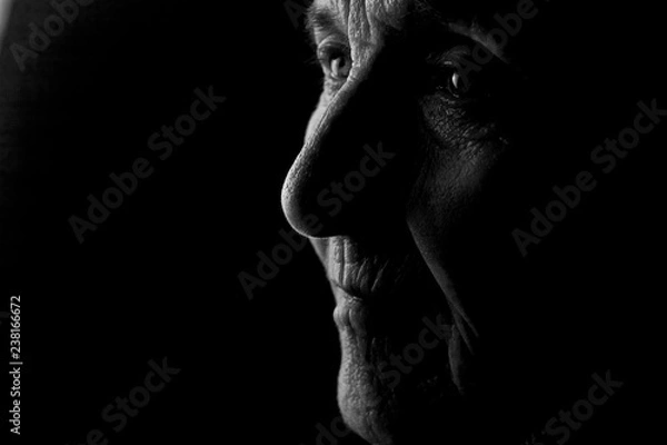 Fototapeta Portrait of an old grandmother's face in profile in the dark