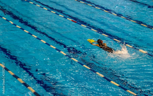 Fototapeta A swimmer in a swimming mask with a swimming board training in a pool.