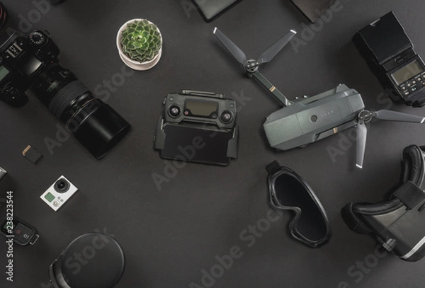 Fototapeta Work space photographer with laptop, digital camera, memory card, action camera, drone, remote controller, phone, VR glasses and camera accessory. Top view on black table background. 