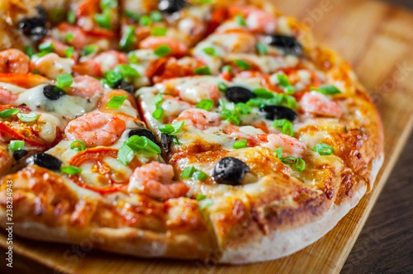 Obraz Pizza with Mozzarella cheese, olives, shrimps, tomato sauce, Spices and Fresh green onion. Italian pizza on wooden table background