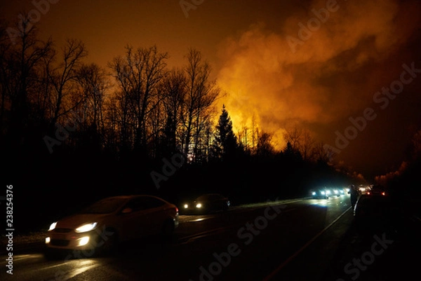 Obraz Forest fire with smoke and a road with cars at night, view from the distance