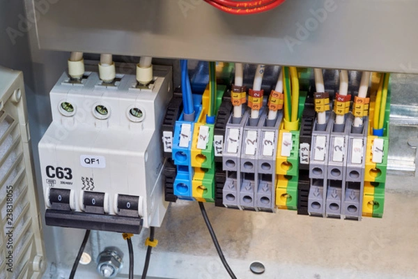 Obraz Modular circuit breaker and a number of terminals in the electrical Cabinet. Electrical wires or cables are connected to the switch and terminals. Reliable and modern power distribution.