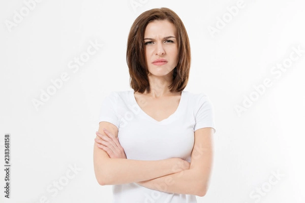 Obraz Upset and angry girl in white blank t shirt isolated on white background. Sad and mad woman with crossed arms . Copy space.