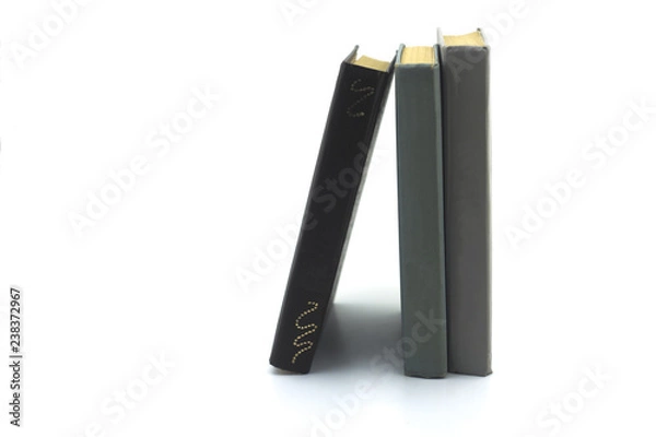Fototapeta two gray and one brown old books standing on a white background close-up