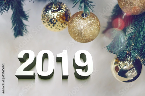 Fototapeta Shiny gold christmas balls on white with pine tree and 3d 2019 text