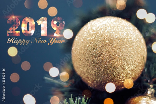 Fototapeta Closeup of gold bauble hanging from a decorated Christmas tree. Shiny happy new year concept with 2019 happy new year text