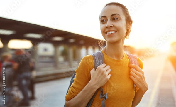 Obraz portrait of a young woman traveler with small backpack on the railway stantion
