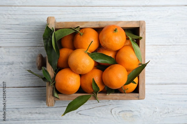 Fototapeta Crate with fresh ripe tangerines on wooden background, top view