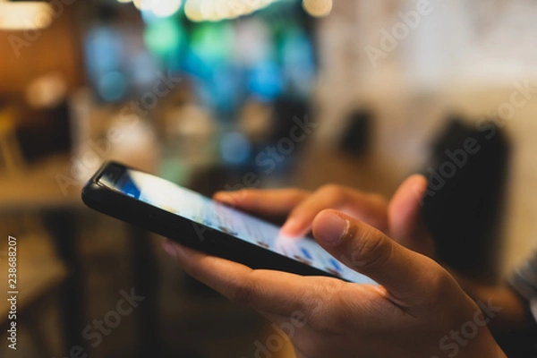 Fototapeta Woman hand using smartphone and laptop with cafe shop sunlight  shade to object beautiful background.