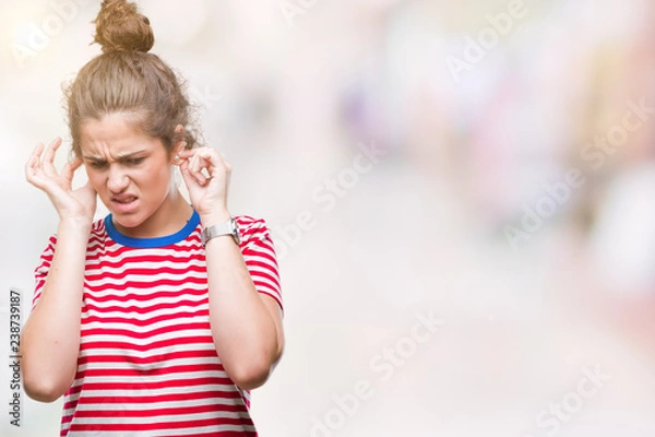 Fototapeta Beautiful brunette curly hair young girl wearing casual look over isolated background covering ears with fingers with annoyed expression for the noise of loud music. Deaf concept.
