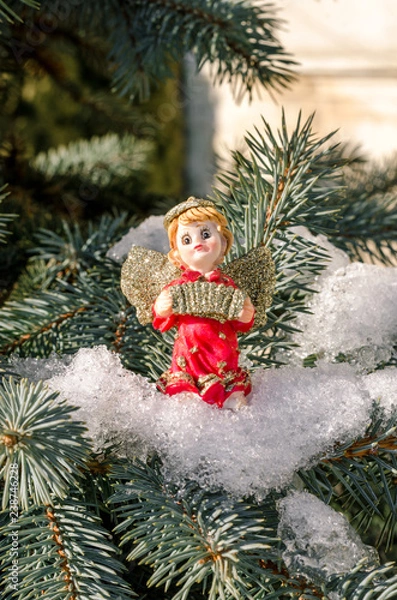 Fototapeta Winter angel figure red new year in the snow on the Christmas tree concept