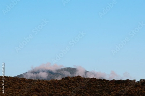 Fototapeta against the blue sky is visible a mountain shrouded in clouds