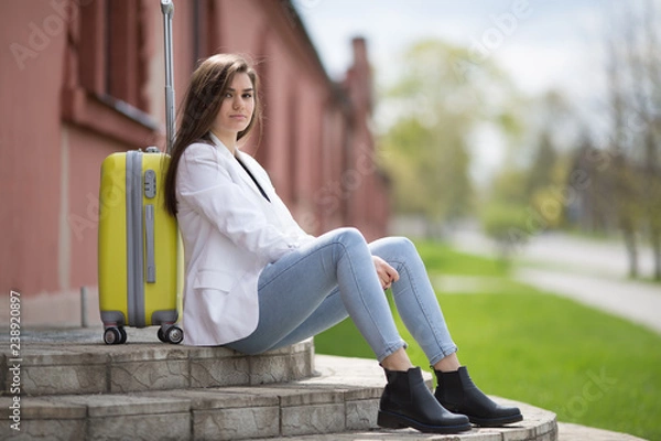 Fototapeta Beautiful fashionable happy girl, hipster, in the terminal at the airport with suitcase.