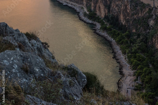 Fototapeta soft focus narrow sea bay aerial photography from above with with rocky stones on foreground and water between mountains on background in twilight darkness evening environment 