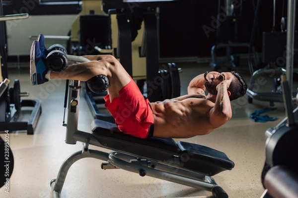 Fototapeta Strong man in the gym doing abs exercises