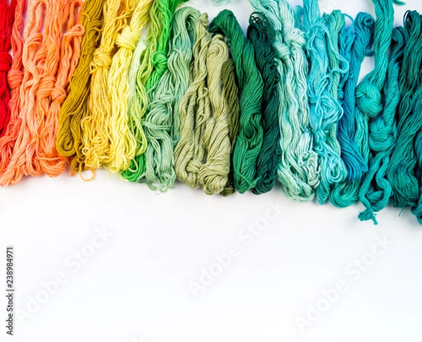 Fototapeta Rainbow color threads for embroidery on a white background.