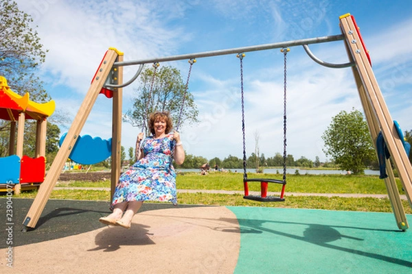 Fototapeta grandmother. old woman riding a swing in the playground
