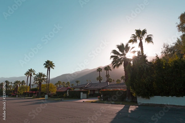Fototapeta Słońce zachodzi za górami przed zmierzchem w Palm Springs, Kalifornia, USA. Strumień światła słonecznego w górach otaczających bulwar miasta Palm Springs przed zachodem słońca.