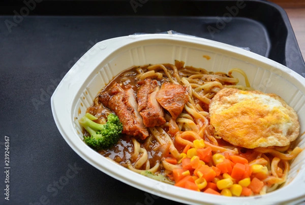 Fototapeta noodle with spicy sauce, sliced chicken, fried egg, broccoli, corn and carrot, instant food, delicatessen, frozen food in mini mart or supermarket ready to eat (selective focus)