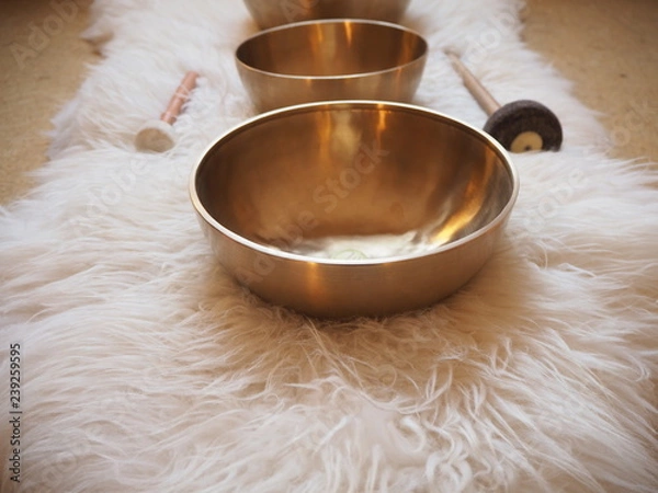 Fototapeta Three singing bowls in a row on a sheepskin for soundhealing, meditation and therapy.