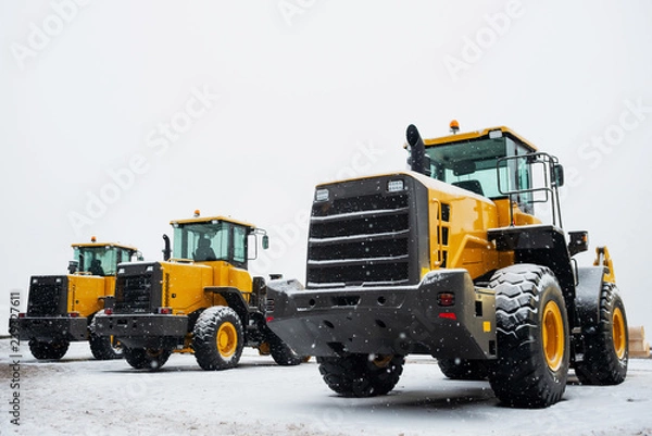 Fototapeta Yellow wheel front loaders. Construction and handling equipment. Heavy diesel tractor, construction machinery, industrial vehicle. Winter time