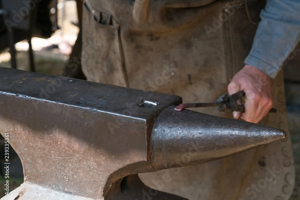 Fototapeta Blacksmith at work with hammer and anvil