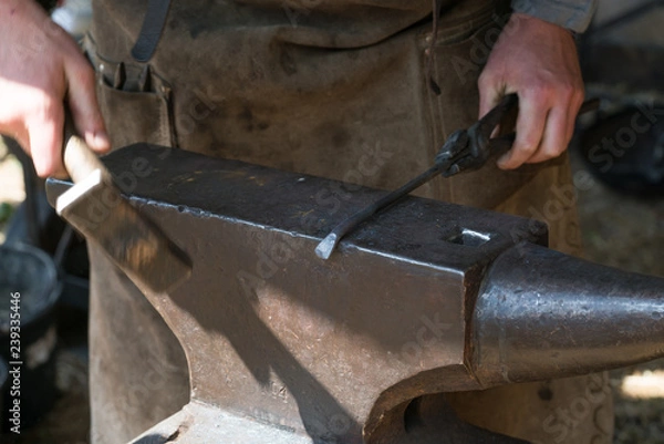 Fototapeta Blacksmith at work with hammer and anvil