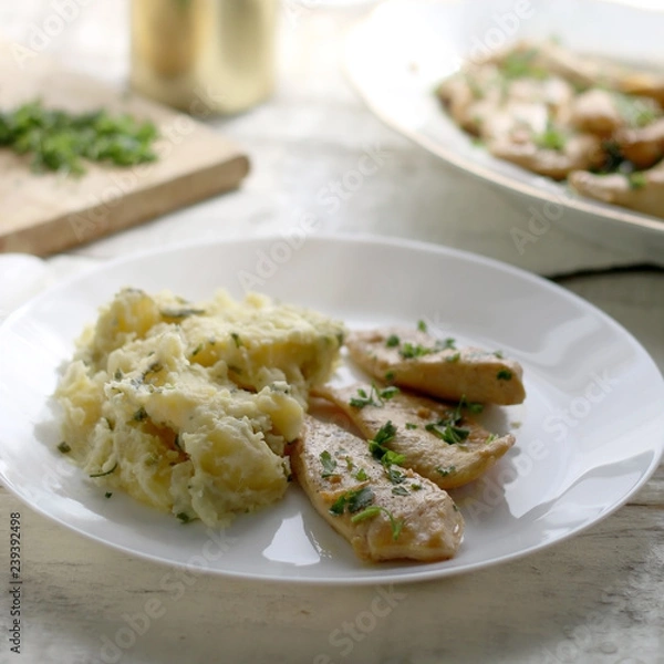 Fototapeta Grilled chicken with fresh parsley and mashed potatoes on a rustic white table. Selective focus.