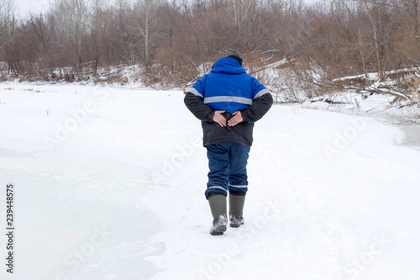 Obraz A man walks in the winter and holds on to his back, a beautiful winter nature.