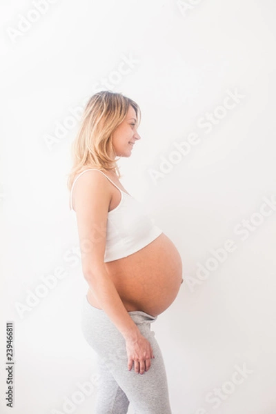 Fototapeta Kobieta w ciąży stoi w pobliżu białej ściany